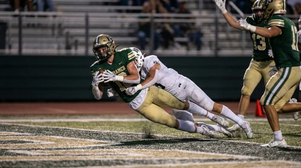 Receiver catching a game winning hail mary touchdown as a defender arrives late