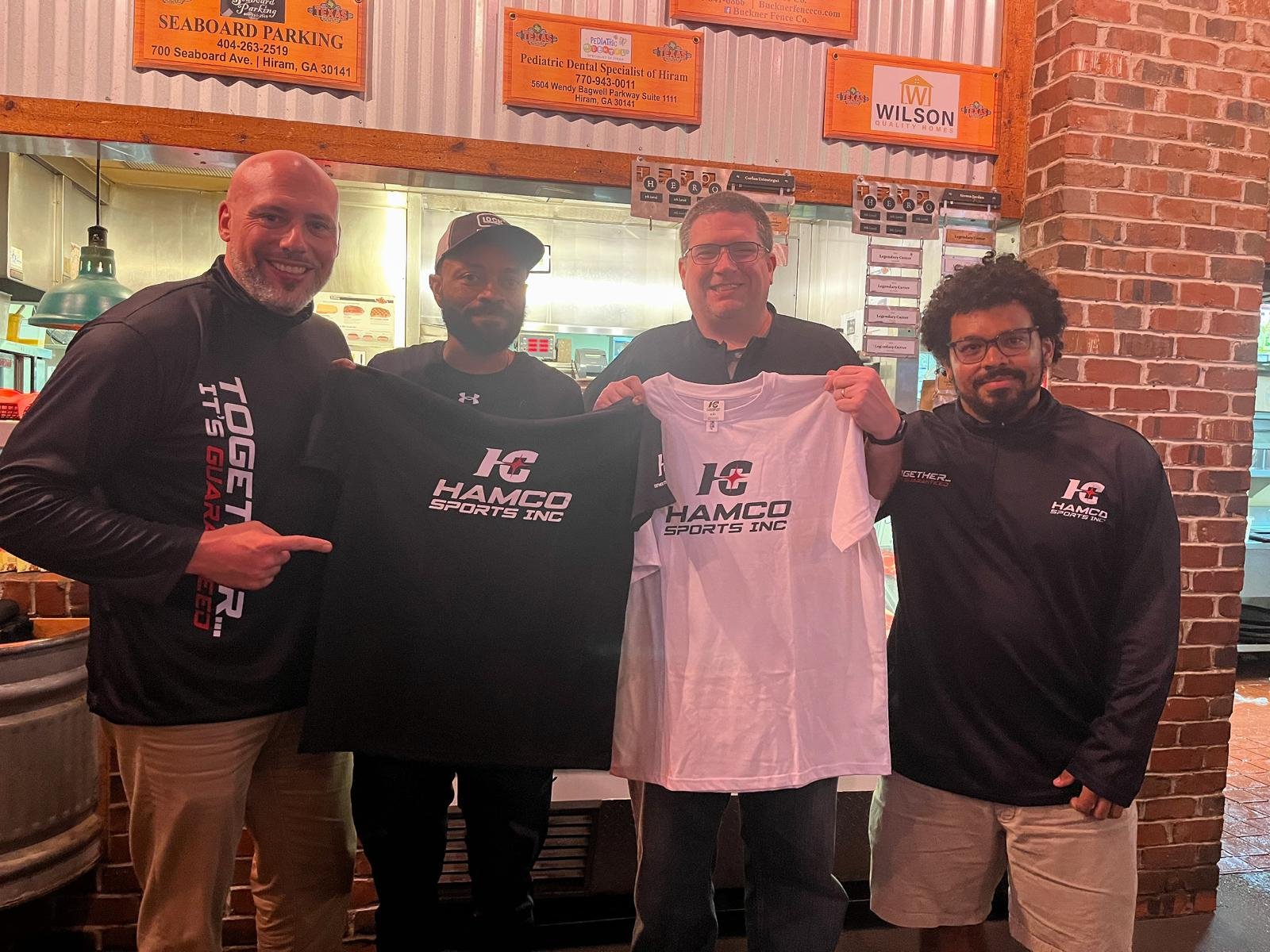 A company representative standing with a group and holding a custom Hamco t-shirt.